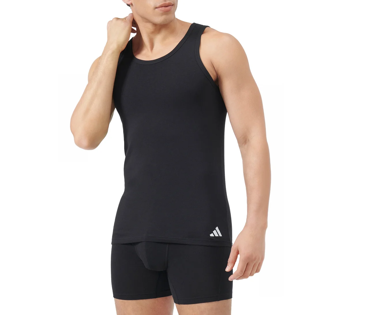Muž v černém tílku s bílým logem Adidas a černých boxerkách, dotýkající se krku, na bílém pozadí.
