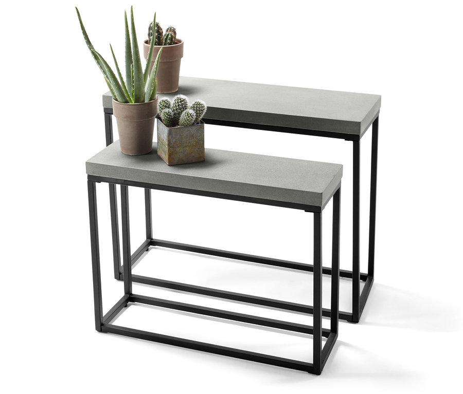 Dva konzolové stolky s betonovými deskami a černými kovovými rámy, na kterých jsou umístěny květináče.