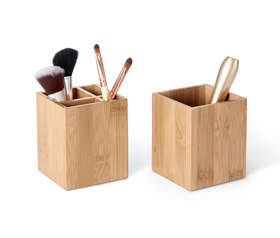 Dva bambusové organizéry, jeden s přihrádkami a štětci na make-up, druhý s lahvičkou.