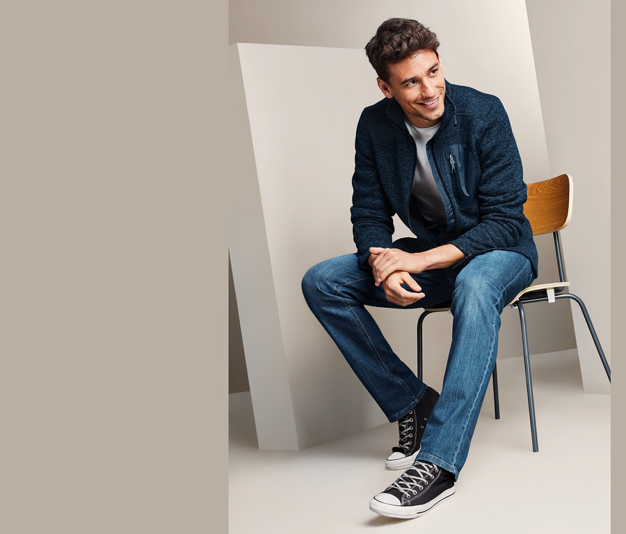 Muž sedí na židli a má na sobě kabát z pleteného fleecu.