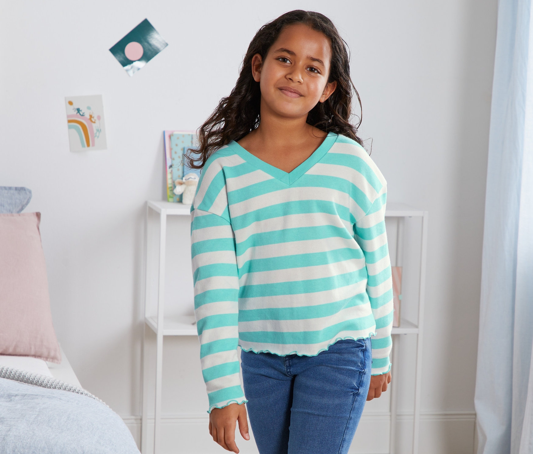 Dívka pózuje v bio bavlněné mikině s modrými pruhy.