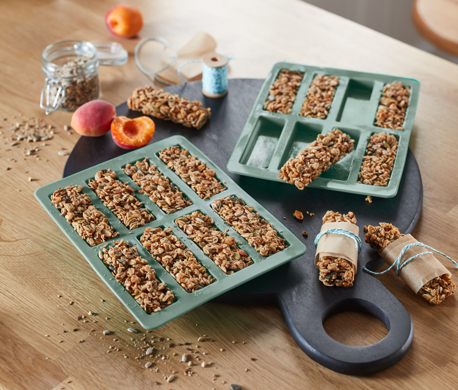 Dvě zelené formy na müsli tyčinky, 2 ks, leží na stole vedle sebe. V jedné formě je pět tyčinek, v druhé osm.