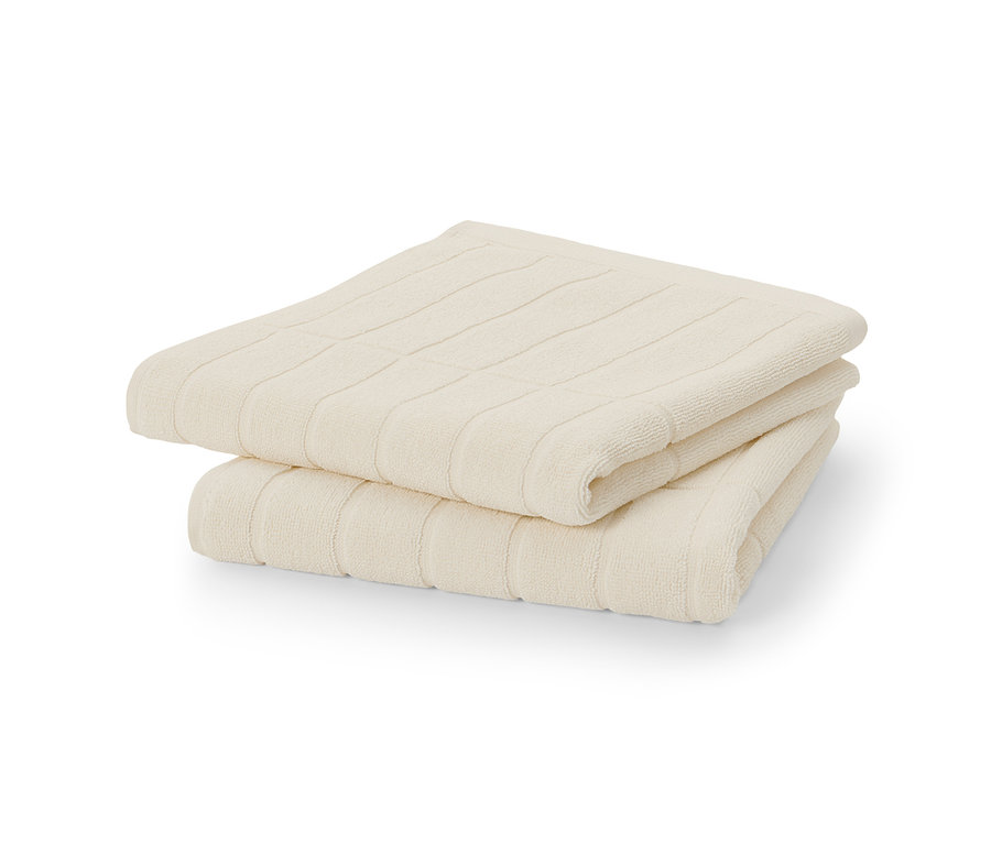 Dva krémově bílé prémiové ručníky složené na sobě.