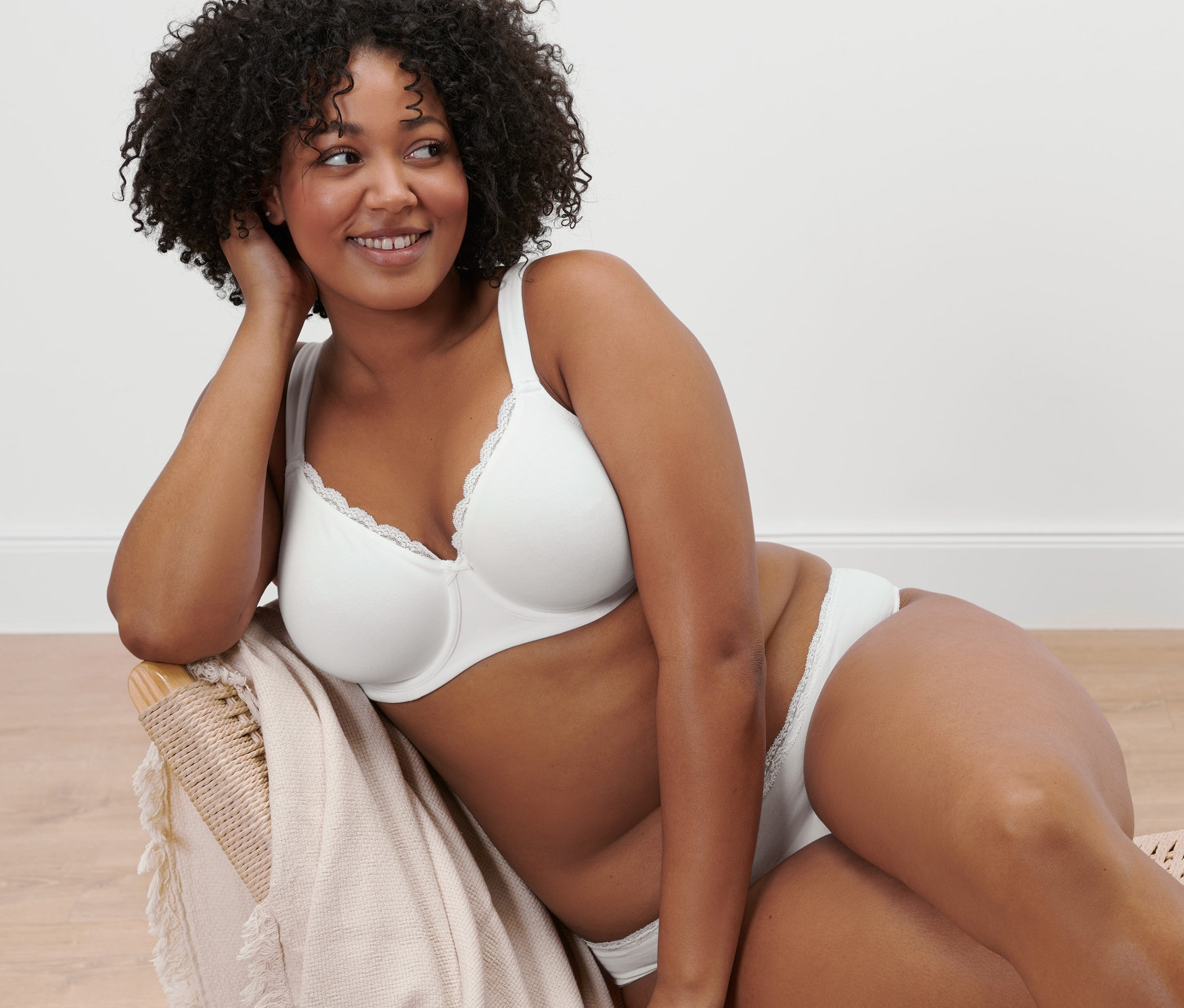 Žena sedí v křesle a má na sobě bílou podprsenku s kosticemi.