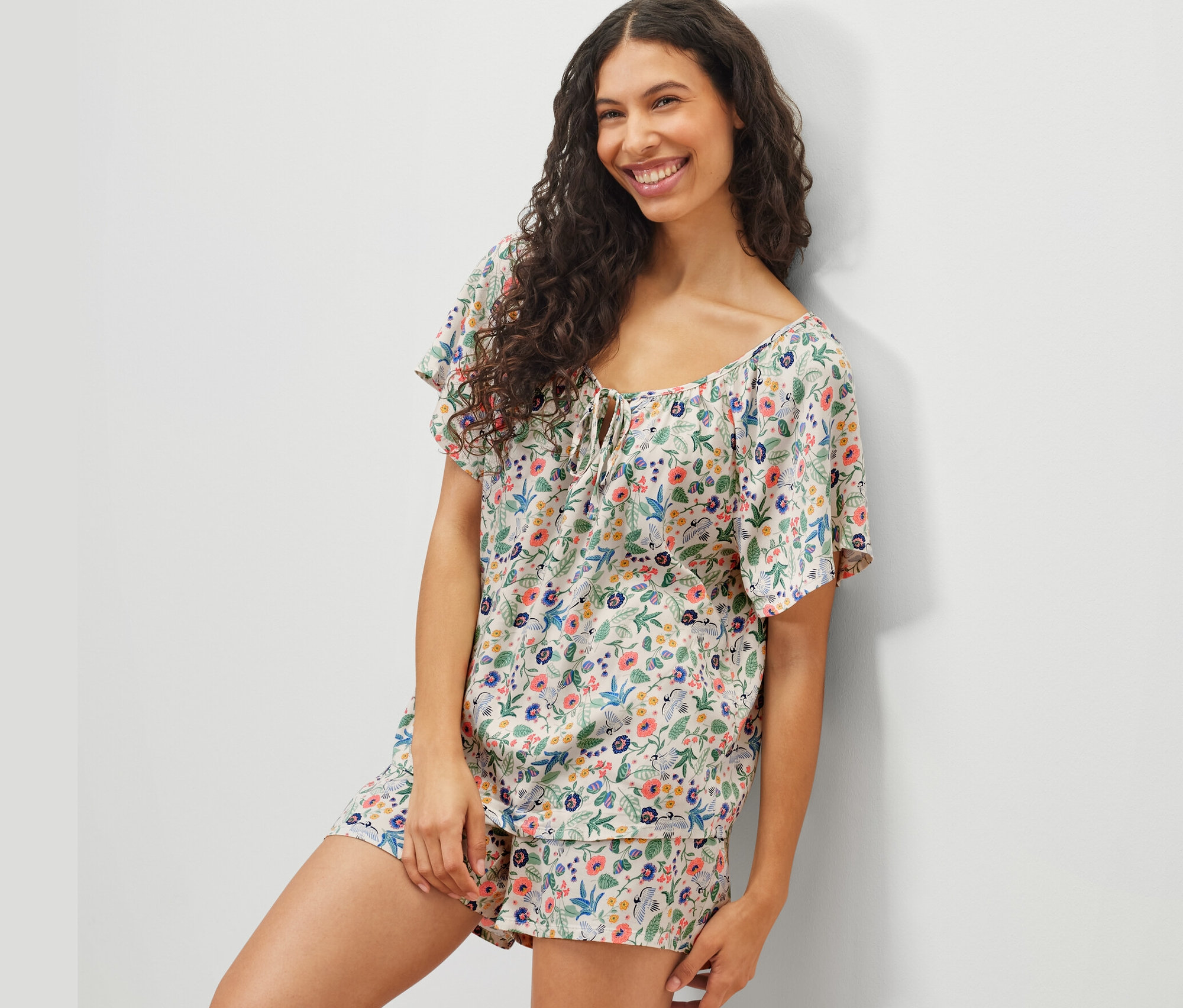 Žena pózuje v krátké pyžamové soupravě s květinovým vzorem.
