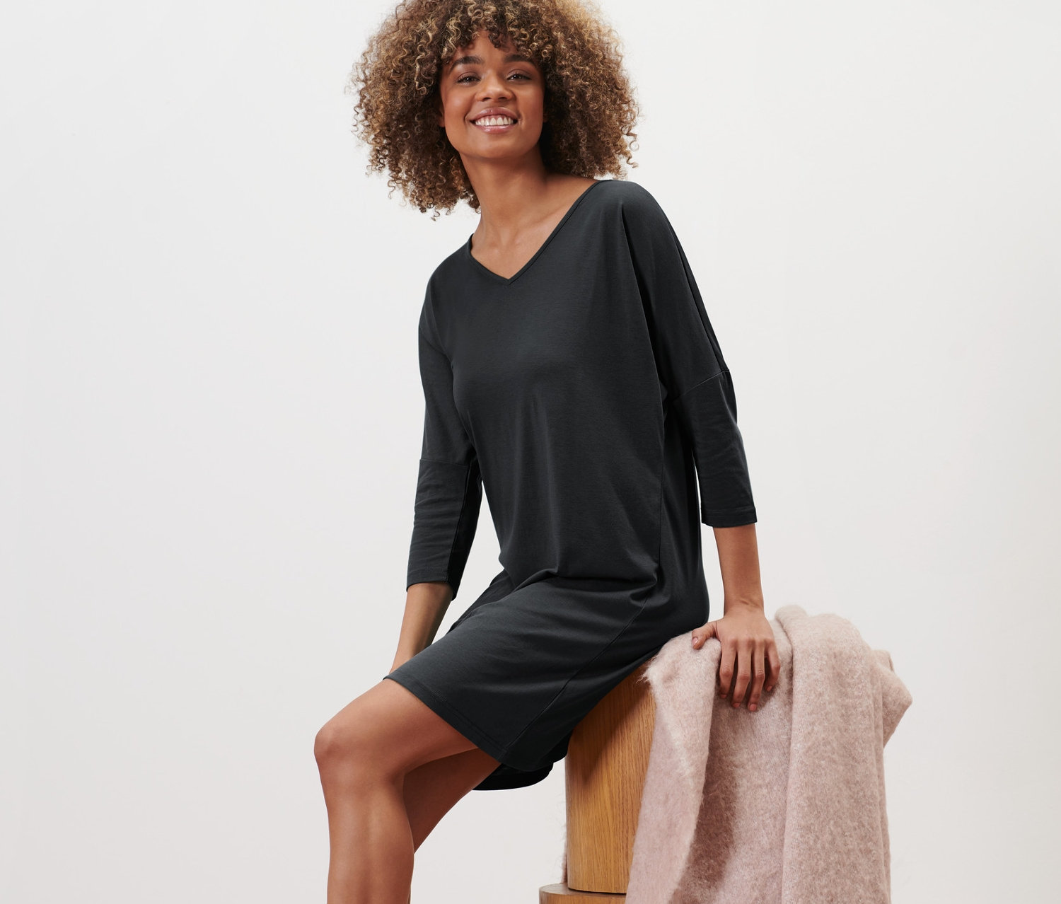 Žena sedí na dřevěných kostkách a má na sobě noční košili.