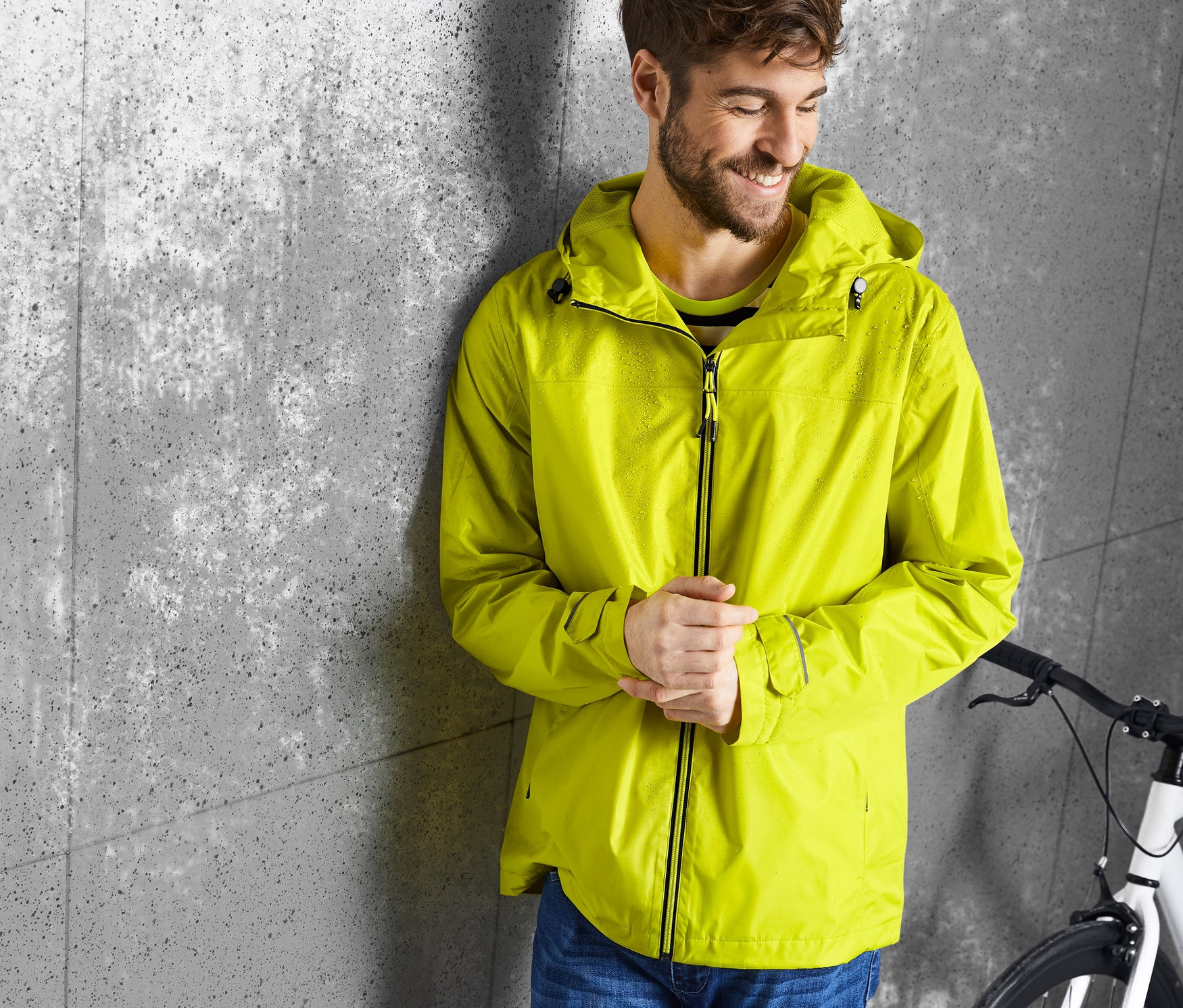 Muž opřený o zeď má na sobě žlutou bundu do deště.