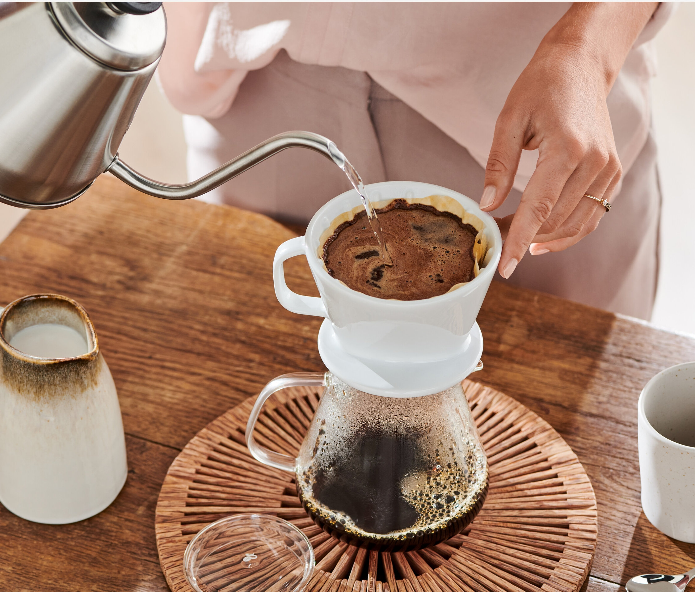 Žena nalévá vodu z konvice do bílého ručního kávového filtru vel. 2 s papírovým filtrem vel. 2, 18x 80 ks.