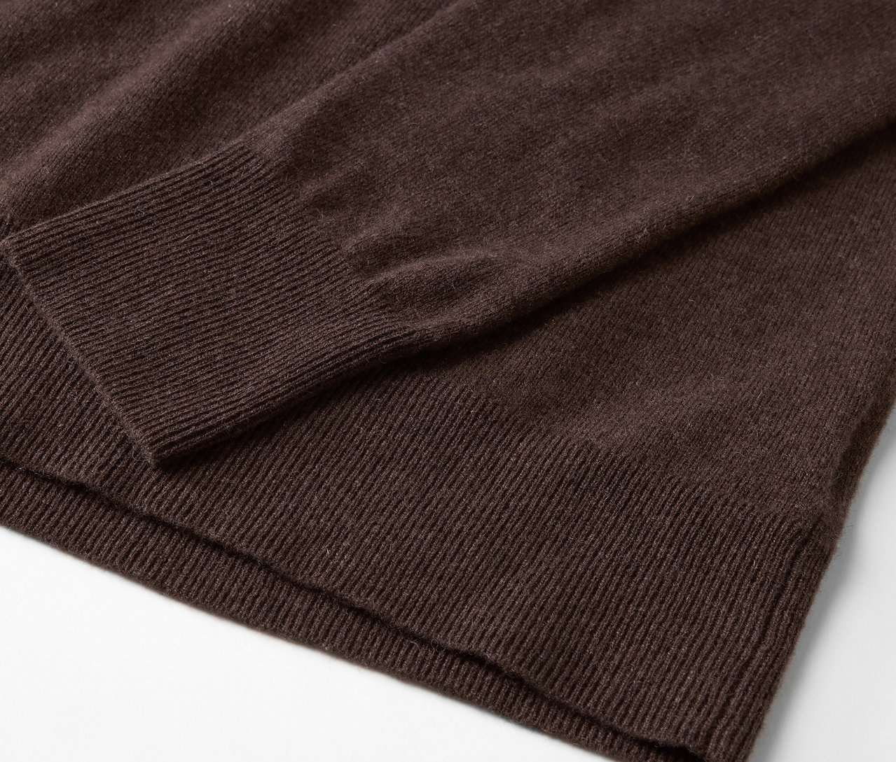 Detail hnědého svetru s dlouhým rukávem.