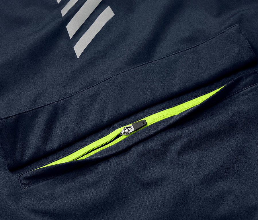 Detail modré cyklistické větrovky Rad-Regenjacke s neonově zeleným zipem na kapse a reflexními prvky.