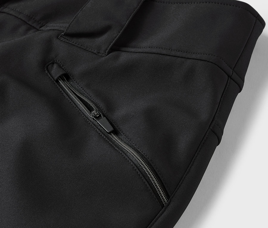 Detail černých kalhot s kapsou na zip.