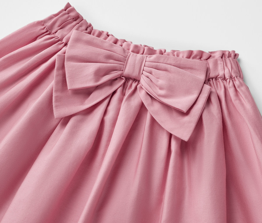 Detailní pohled na dětskou tkanou sukni s velkou mašlí.