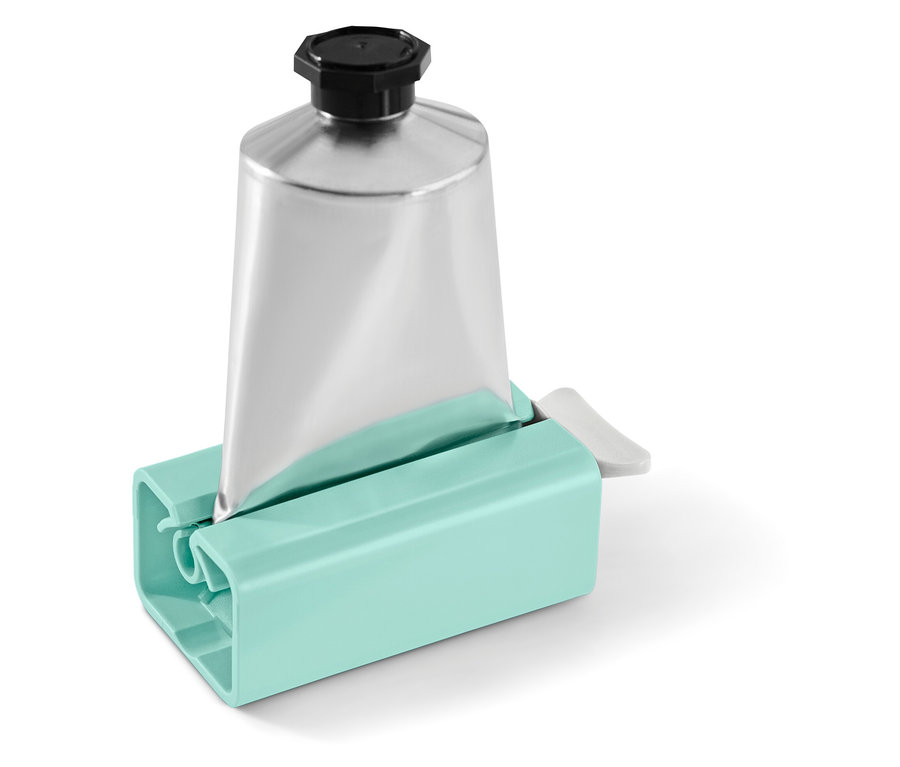 Stříbrná tuba s černým uzávěrem v tyrkysovém vytlačovači na tuby.