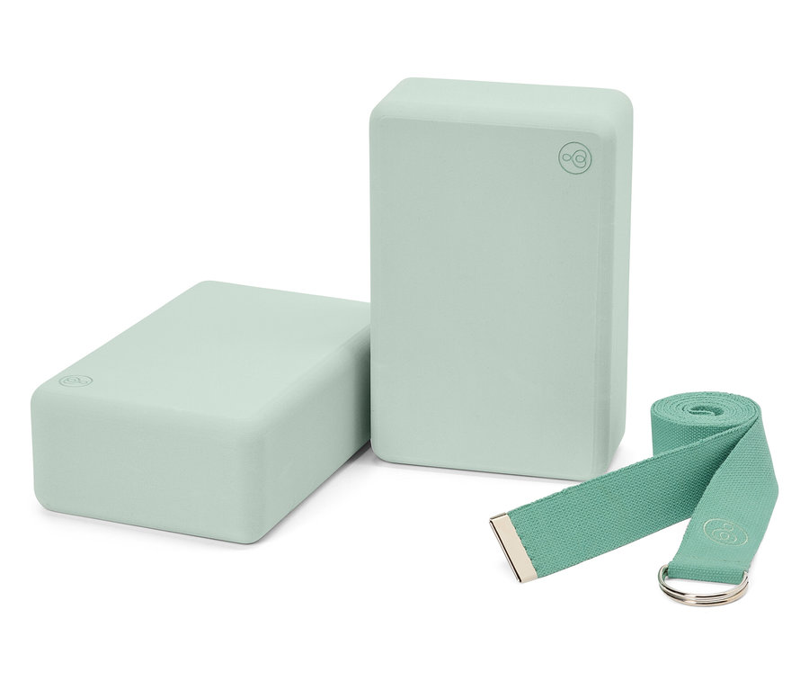 Dva světle zelené jógové bloky a odpovídající popruh.