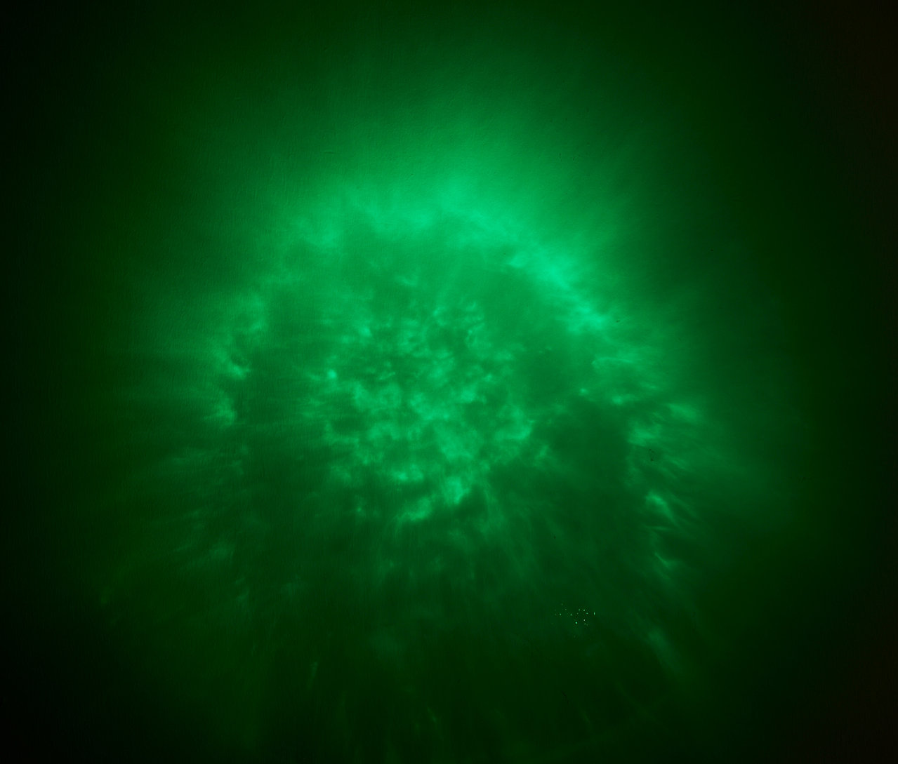 Zelené světlo s rozptýleným vzorem na tmavém pozadí.