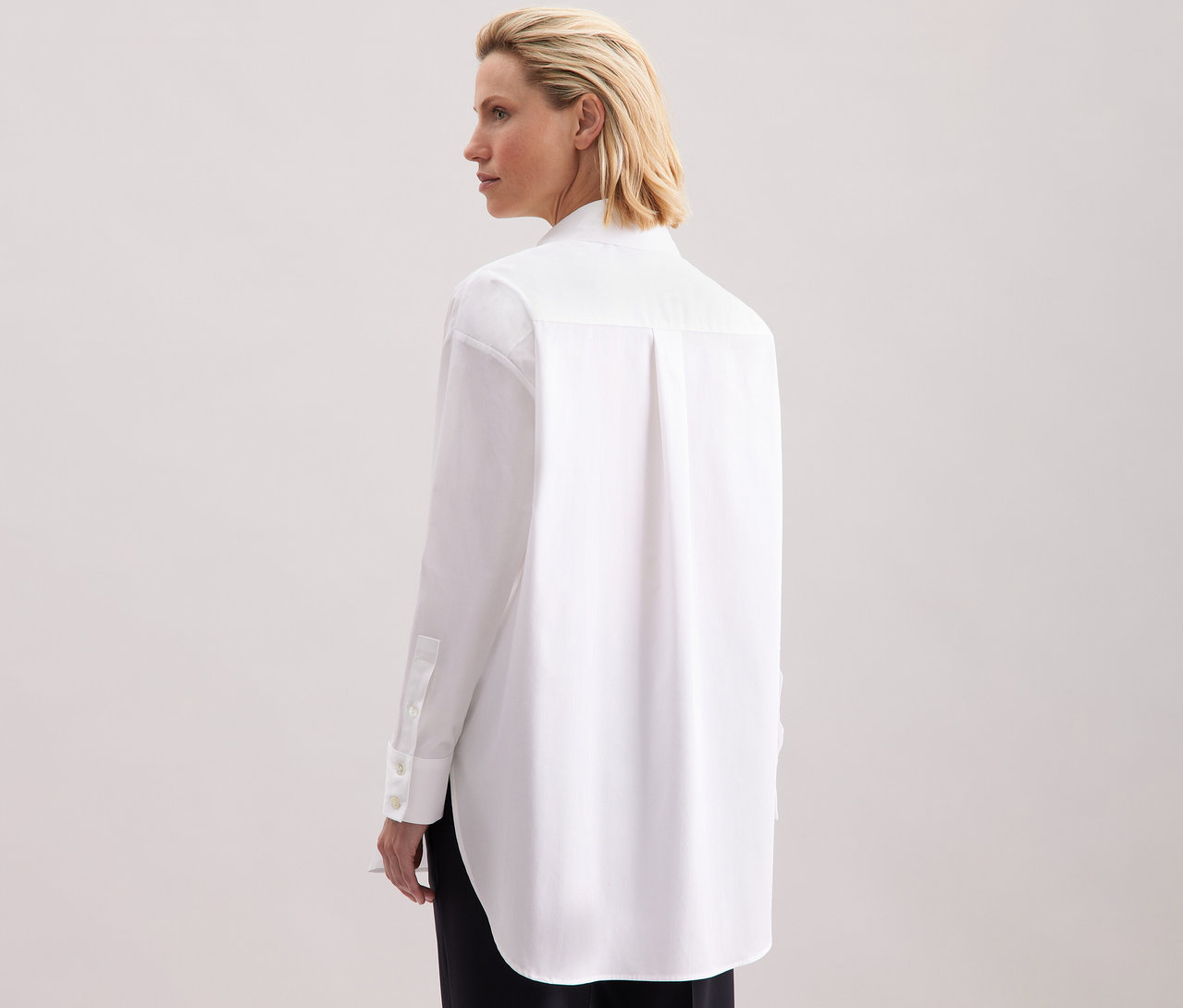 Žena zezadu v bílé dlouhé halence oversize Seidensticker.