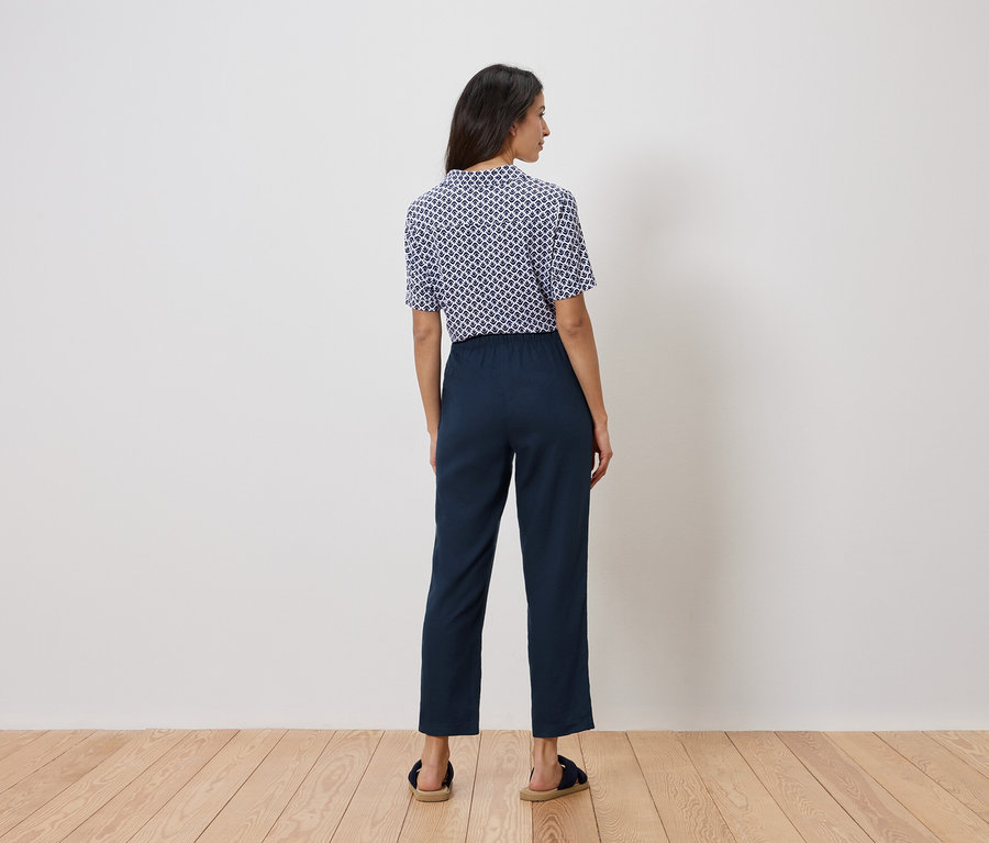 Žena stojí zády ke kameře, má na sobě modrobílý top a tmavě modré kalhoty.