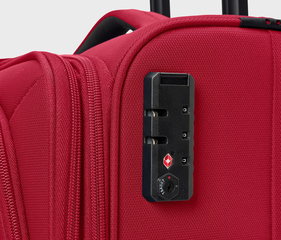 Detail červeného kufru s číselným zámkem.