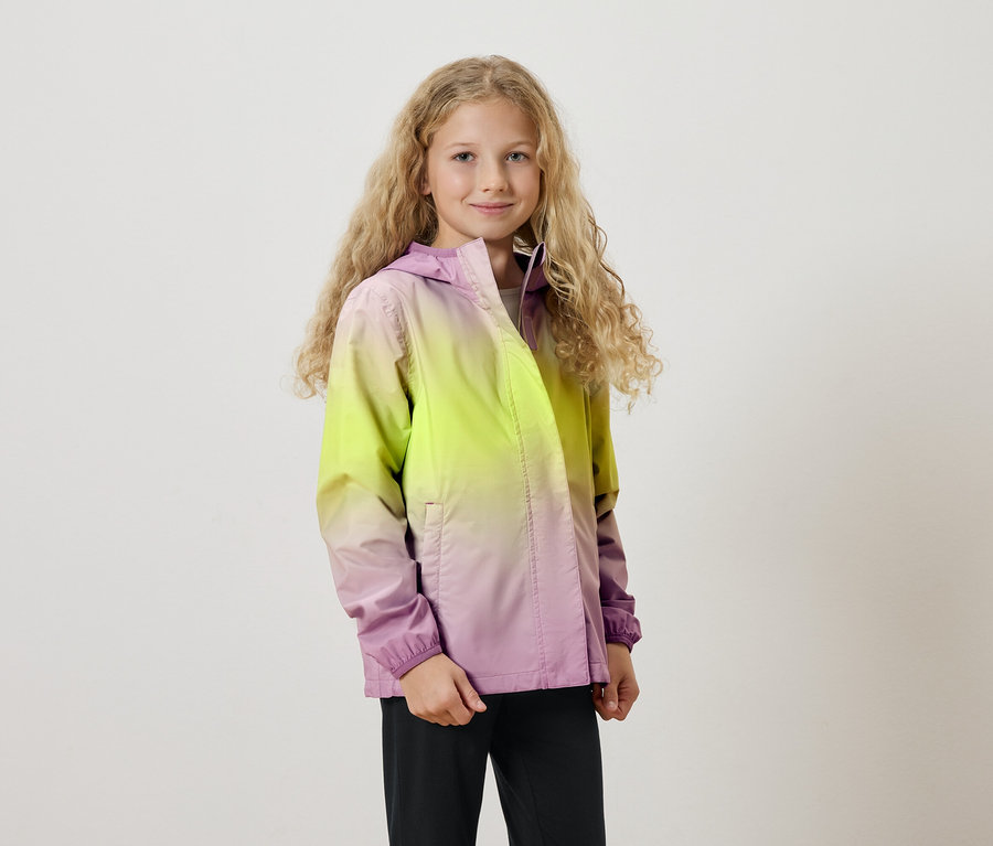 Dívka s dlouhými blond kudrnatými vlasy má na sobě bundu s kapucí s barevným přechodem ze žluté do fialové.
