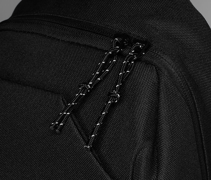 Detailní záběr na černý batoh se zipem a stahovací šňůrkou.
