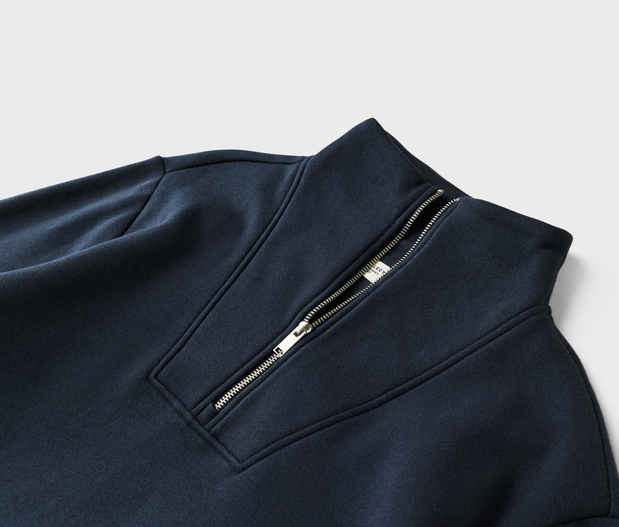 Detailní záběr na tmavě modrou mikinu se zipem u krku.