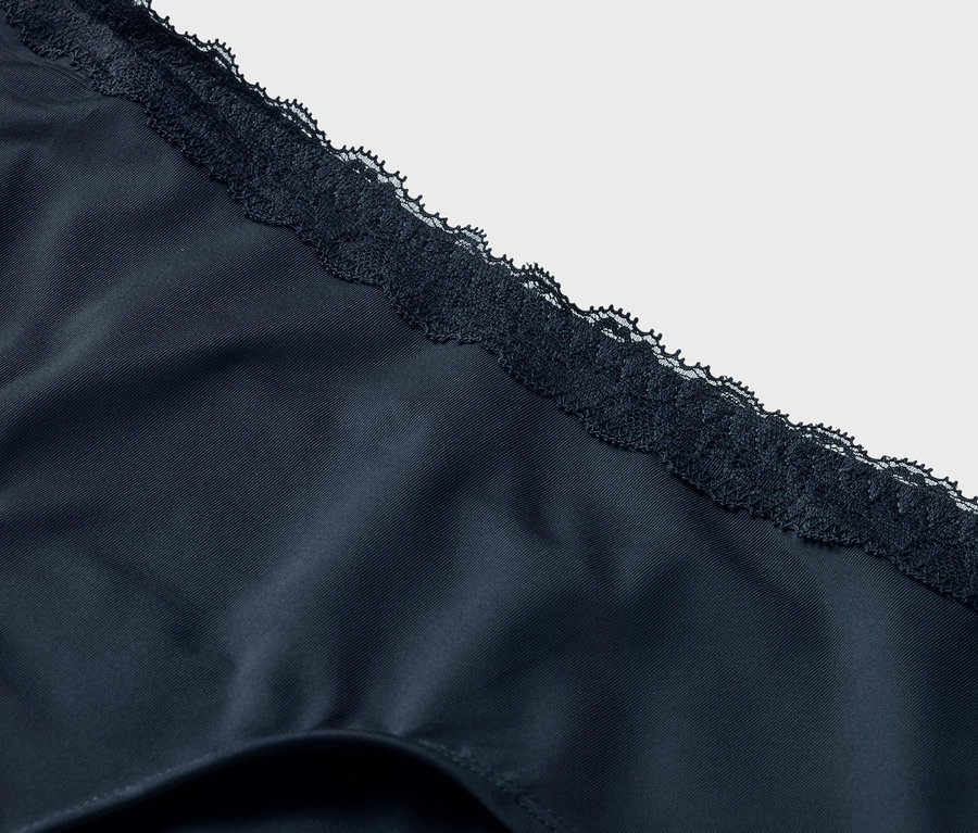 Detailní záběr na tmavě modré spodní prádlo s krajkovým lemem.