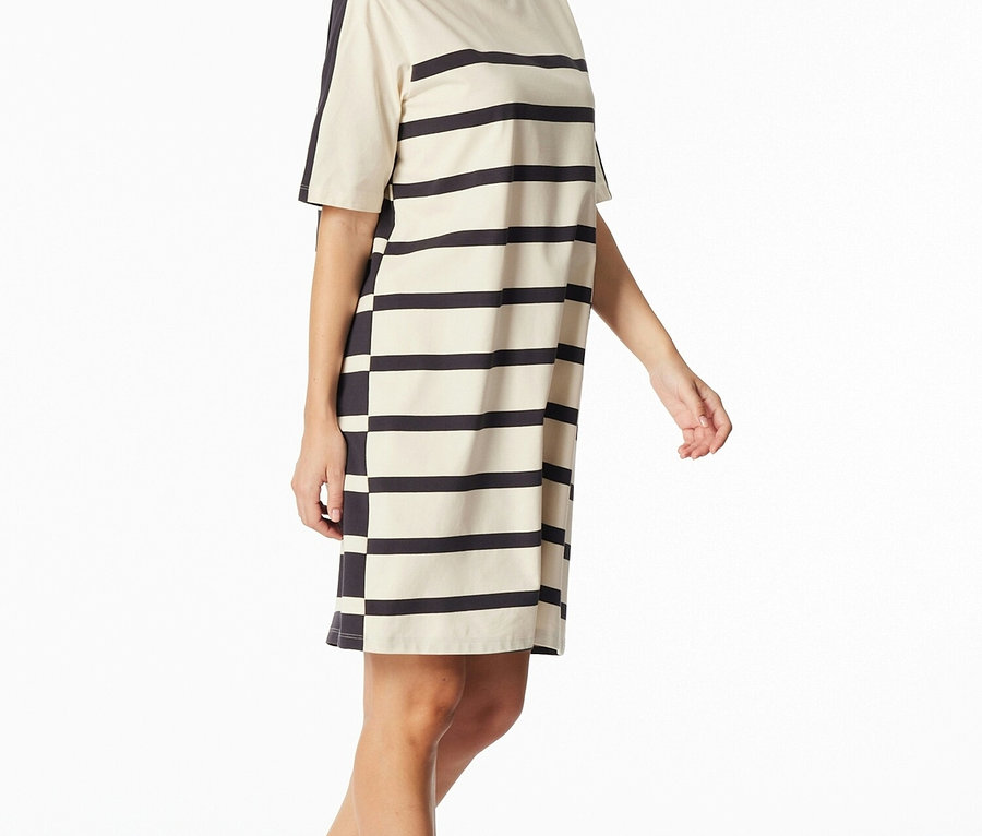 Žena má na sobě pruhované tričkové šaty s krátkým rukávem v černé a krémové barvě.