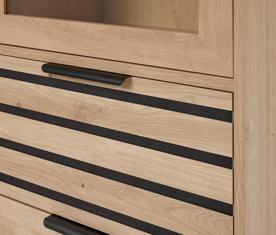 Detailní záběr světle hnědé dřevěné skříňky se zásuvkami s černými vodorovnými akcenty a černými vodorovnými úchyty.