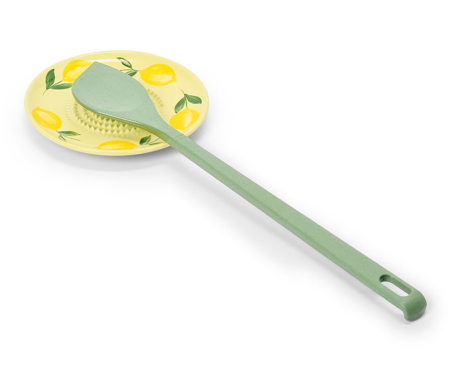 Světle zelená vařečka leží na žluté podložce s citronovým vzorem.