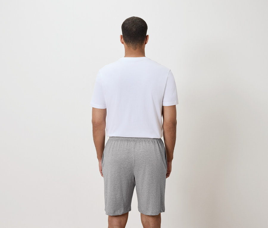 Pohled zezadu na muže v bílém tričku a šedých šortkách.