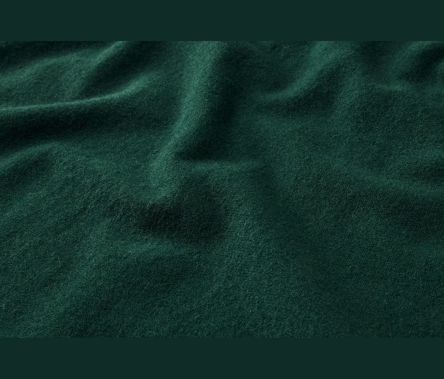 Tmavě zelená, měkká látka s jemnými záhyby a texturou.