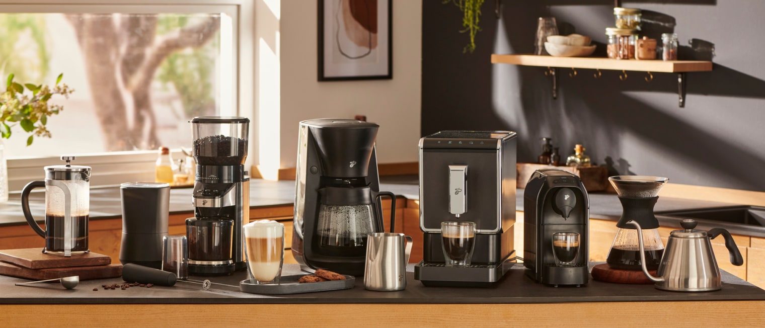 Verschiedene Kaffeemaschinen, Milchkännchen und Tassen auf einer Küchenablage