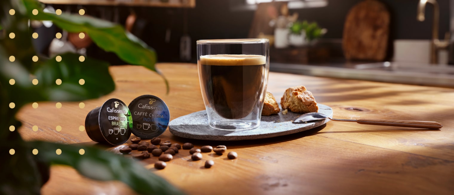 Glas Kaffee steht neben zwei Kapseln Caffissimo auf dem Tisch','Enter picture alt'}