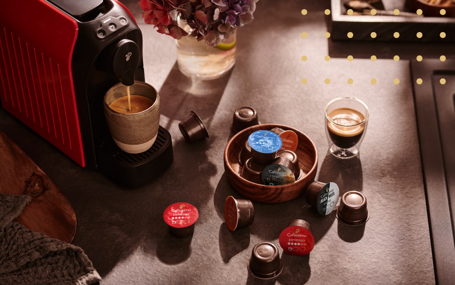 Cafissimo Kapseln und Maschine mit einem Glas Kaffee steht auf einem Tisch